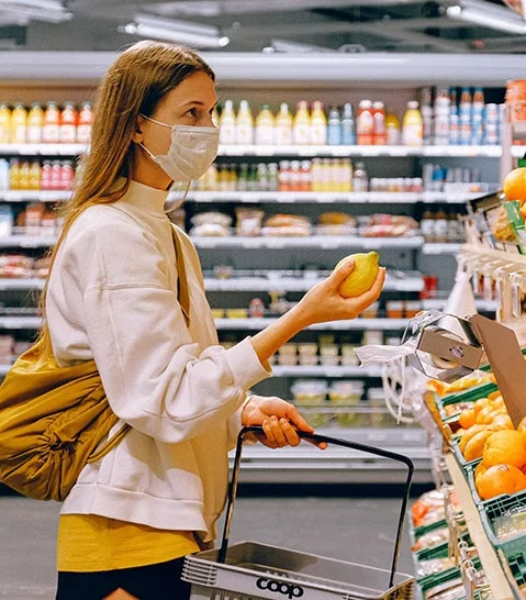 Woman holding a lemon inside a grocery store